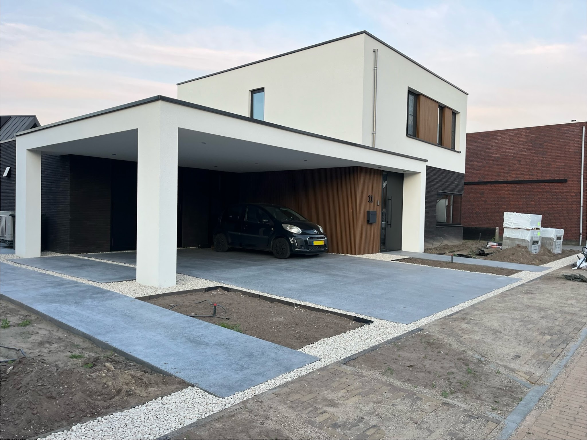 Afgewerkte betonnen oprit bij een carport