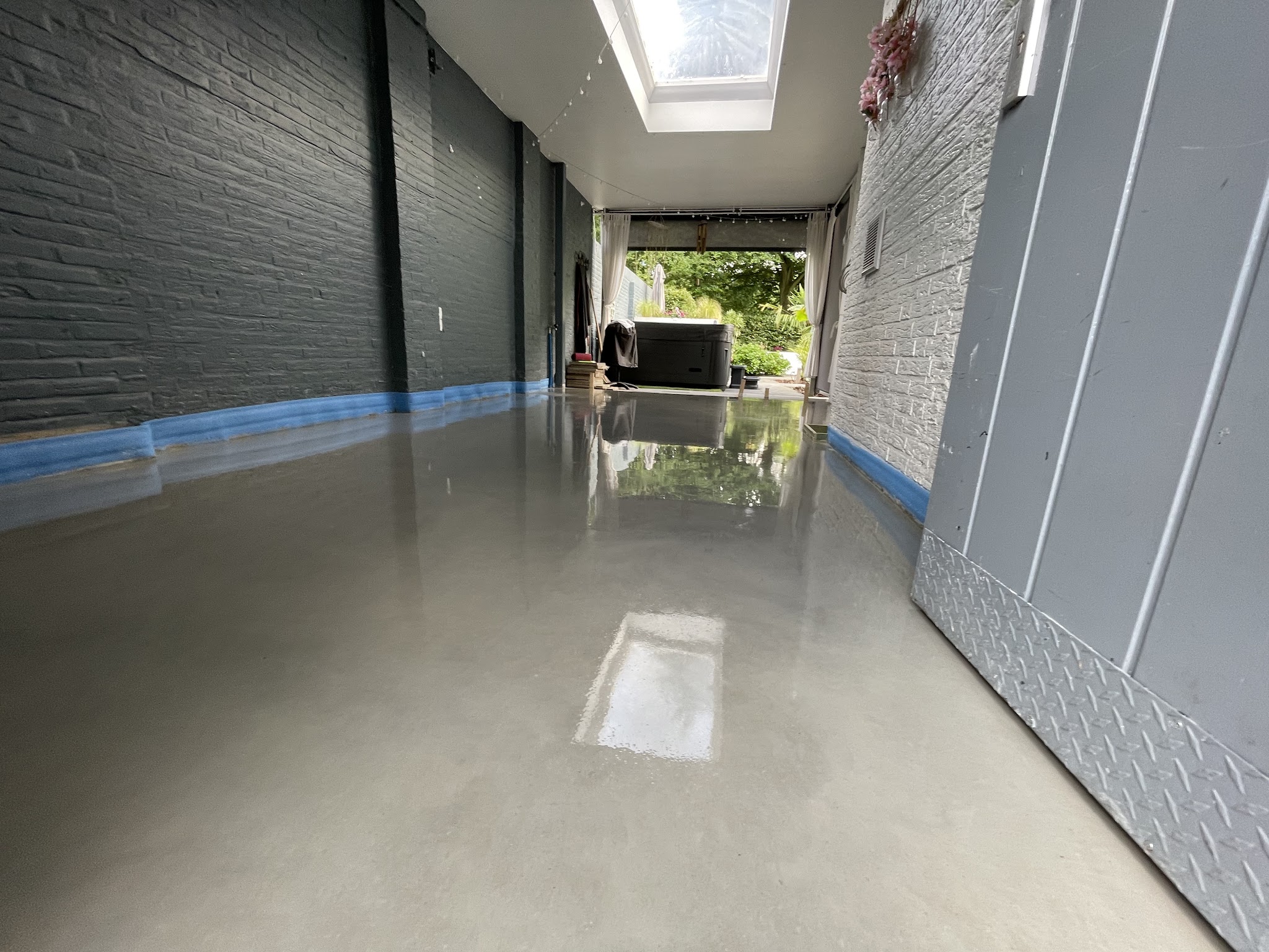 Glanzend afgewerkte betonvloer in een doorloop naar de tuin